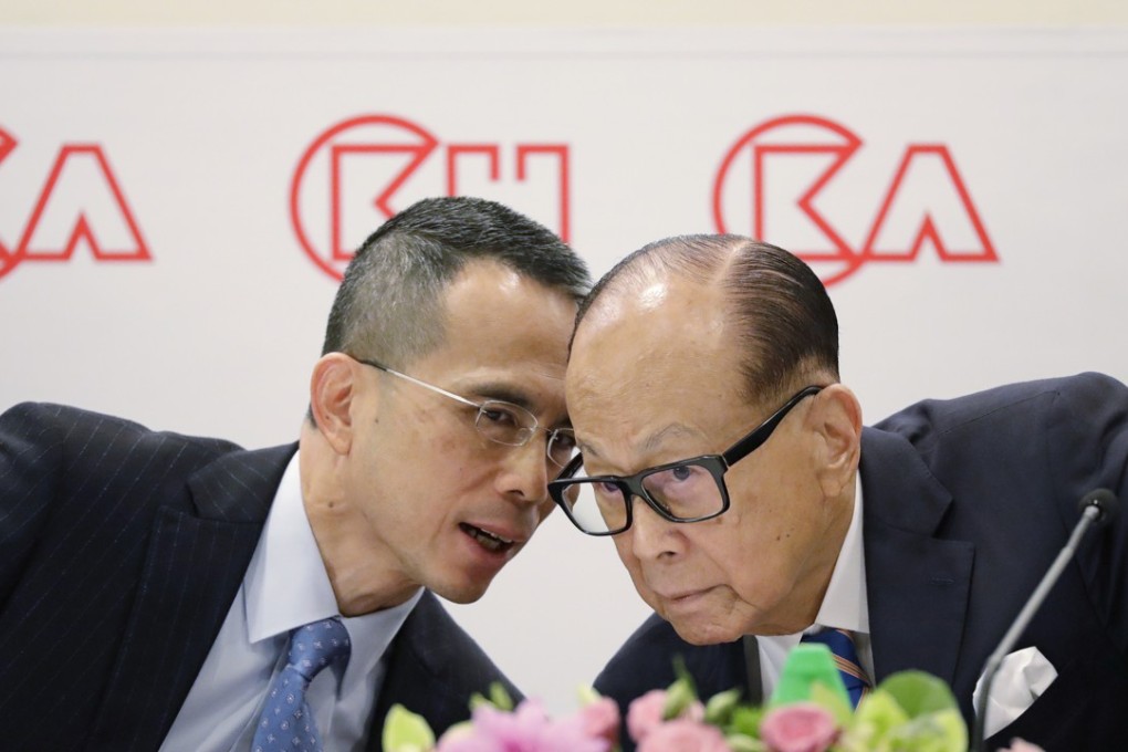 Victor Li, left, speaks with his father, Hong Kong tycoon Li Ka-shing, at a press conference on March 16. The eldest son took the reins from his father at his retirement in May. Photo: AP