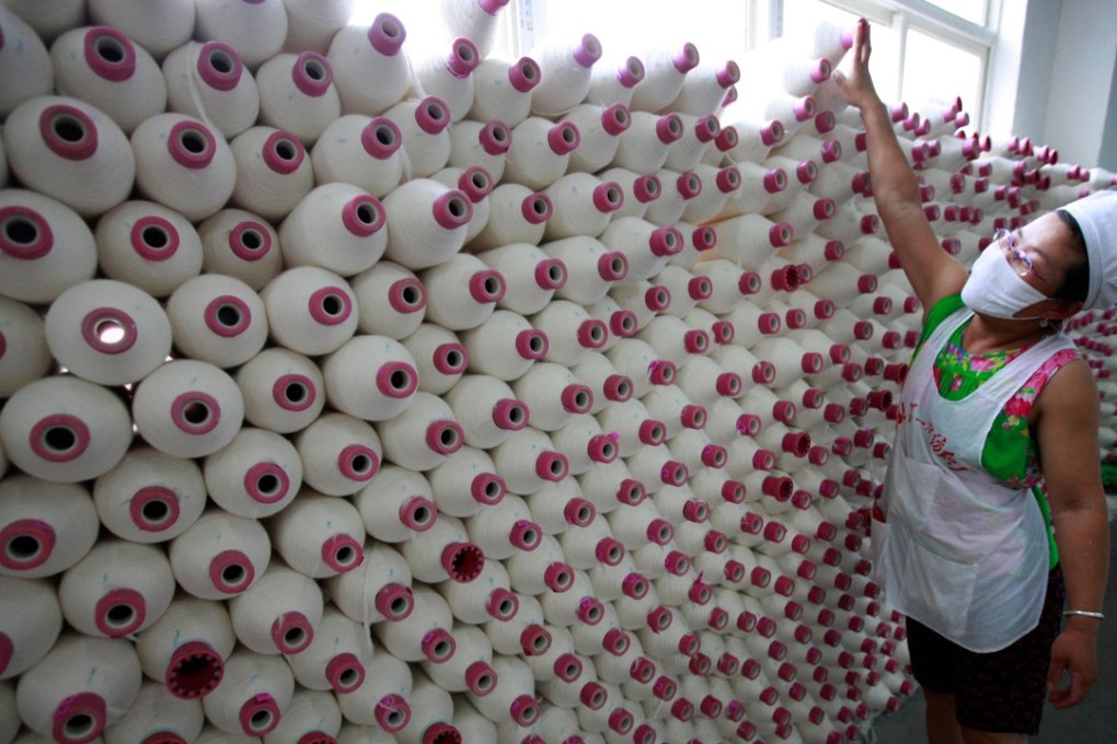 A factory worker with spools of cotton in Huaibei, in eastern China’s Anhui province. Photo: AFP