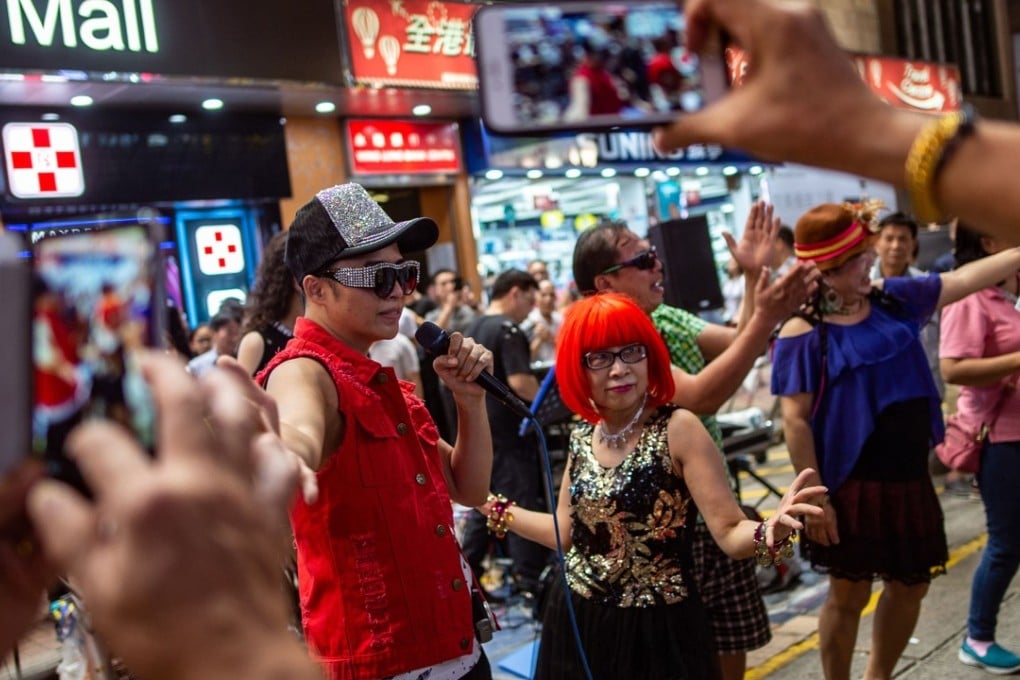 Singers pose for photographs after their performance on Sai Yeung Choi Street South on July 28, the day before all such performances in the Mong Kok pedestrian zone came to an end after 18 years. Photo: AFP
