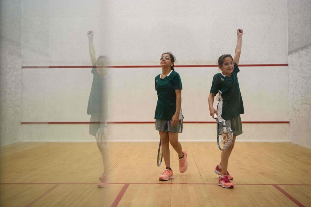 Sabah Husryeh (right) a Syrian member of Squash Dreamers raises her hand after catching the ball as she plays against her sister Raghda Husryeh. Photo: AFP
