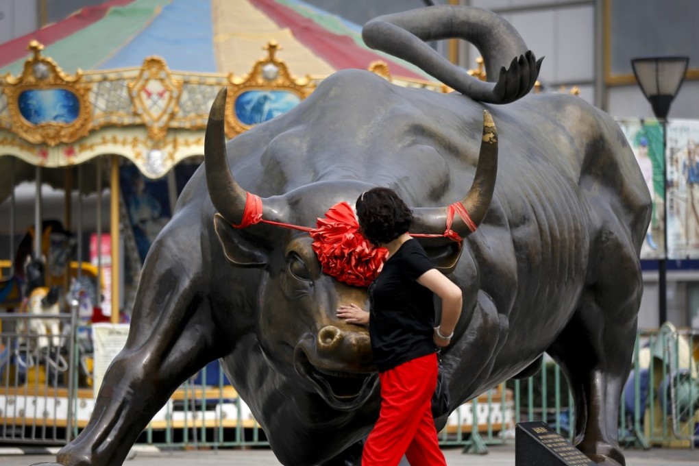 A woman touches a bull statue on display outside a mall in Beijing on June 18. The Shanghai Composite Index and Shenzhen Composite Index have slid nearly 25 per cent in a month. Photo: AP