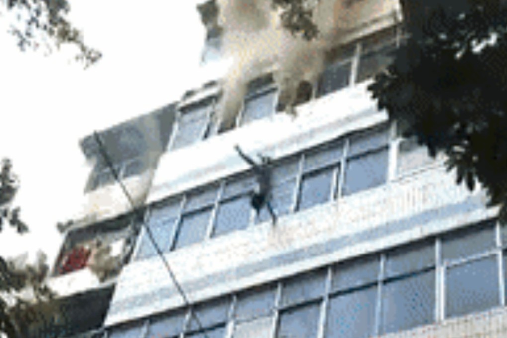 The child is thrown from the burning building, landing safely below. Photo: Handout