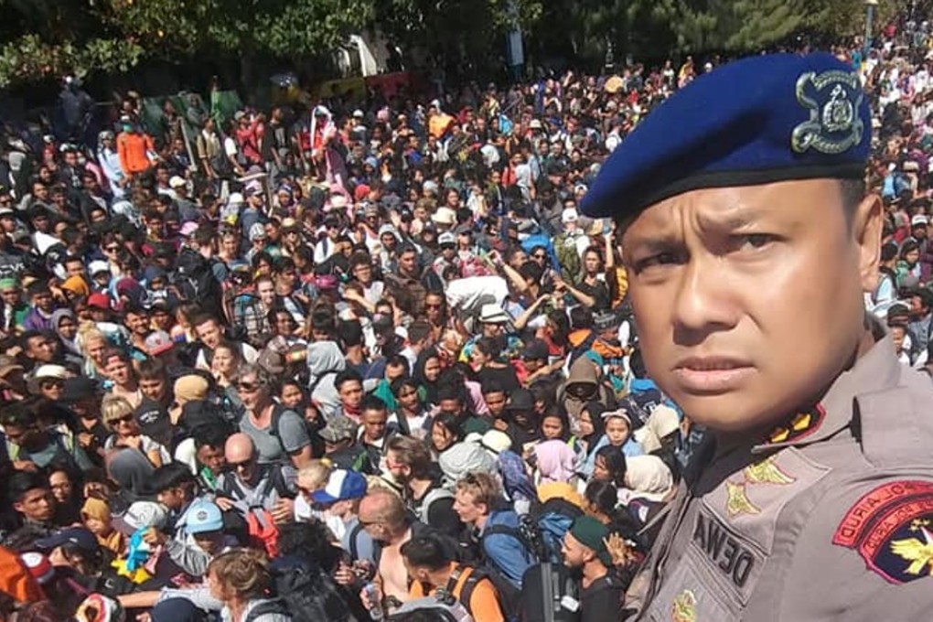 Chief Water Police of Lombok Dewa Wijaya takes a picture in front of hundreds of people trying to leave the Gili Islands after an earthquake in Gili Trawangan, Lombok, Indonesia. Photo: Reuters
