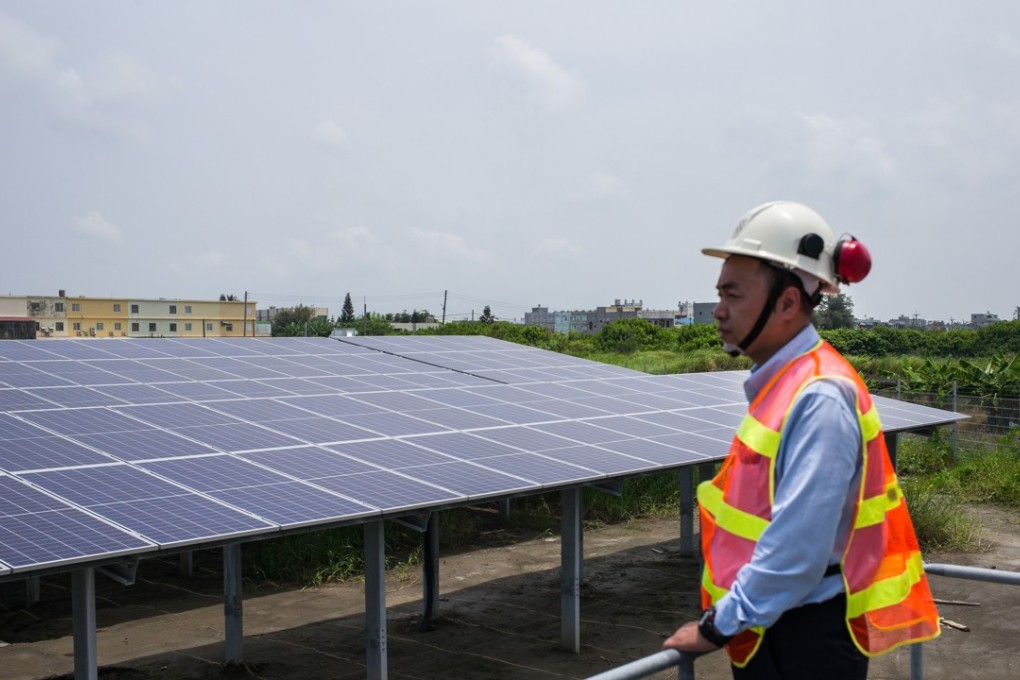 A worker looks on as solar panels stand at a Vena Energy solar-power installation in Yunlin county, Taiwan. Photo: Bloomberg