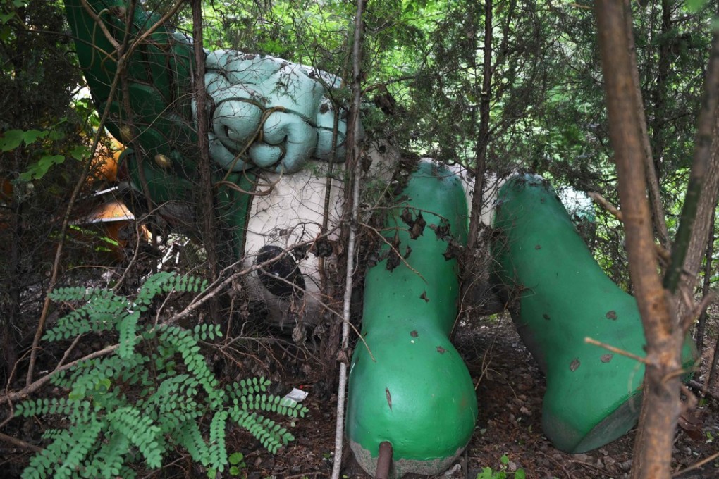 A Nini doll, one of five mascots for the 2008 Summer Olympics, lies among trees behind an abandoned mall in Beijing, on July 20, 2018, a decade after the Chinese capital hosted the Games. Picture: AFP