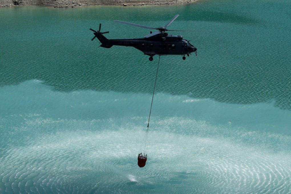 A Swiss Air Force Super Puma helicopter loads water for cows. Photo: Reuters