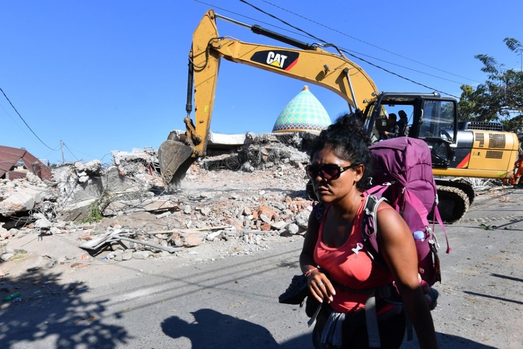 A tourist walks past a damaged mosque as search and rescue teams continue to look for earthquake survivors in Bangsal, North Lombok. Photo: AFP