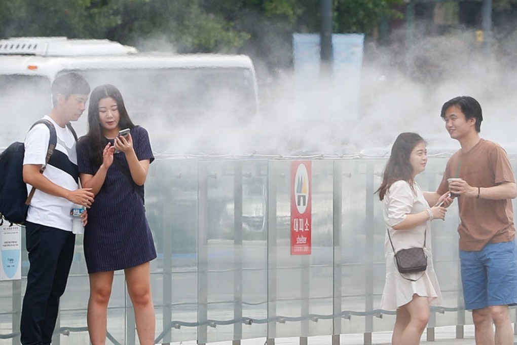 People cool themselves near a misting fountain at Gwanghwamun Square in Seoul. Photo: Xinhua