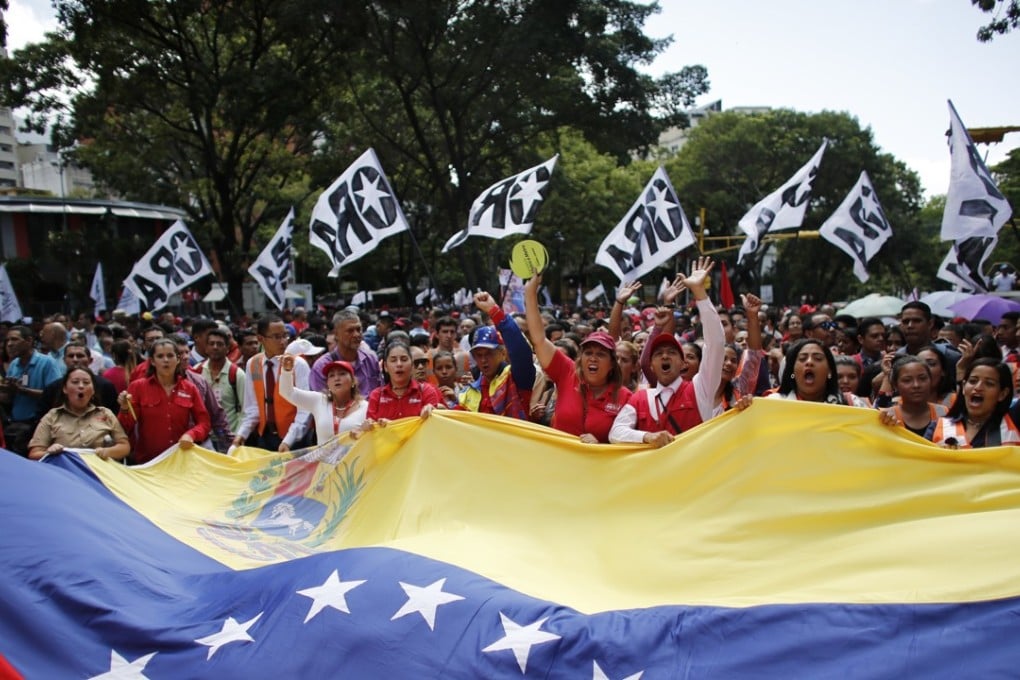 Supporters of Venezuela's President Nicolas Maduro held a giant national flag while marching to the presidential palace in Caracas on Monday. Maduro dodged an apparent assassination attempt over the weekend. Photo: AP