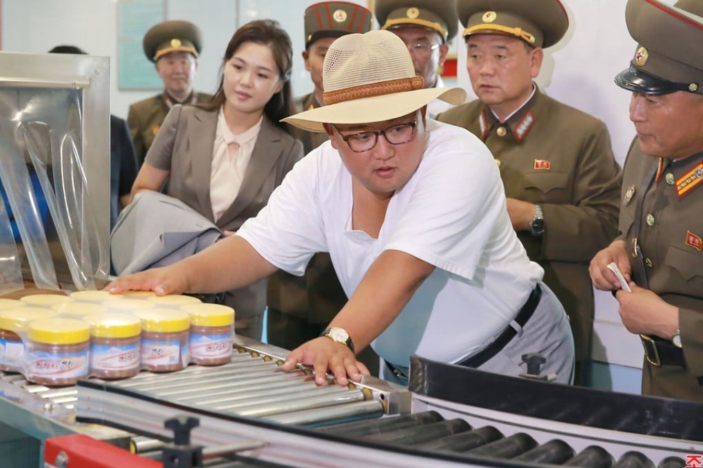 North Korean leader Kim Jong-un asks a military officer a question during a visit to a fish pickling factory, as wife Ri Sol-ju, holding his suit jacket, looks at some machinery, in this undated photo released by North Korea’s official Korean Central News Agency. Photo: KCNA via Reuters