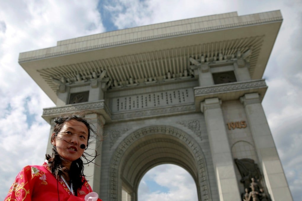A guide wearing a traditional dress speaks to visitors at the Arch of Triumph in Pyongyang. Photo: Reuters