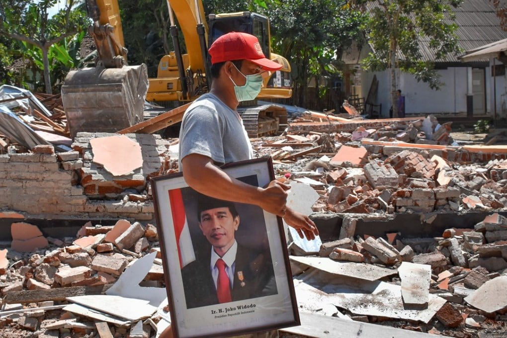 A man carries a framed picture of Indonesian President Joko Widodo from a school damaged by the earthquake. Photo: Reuters