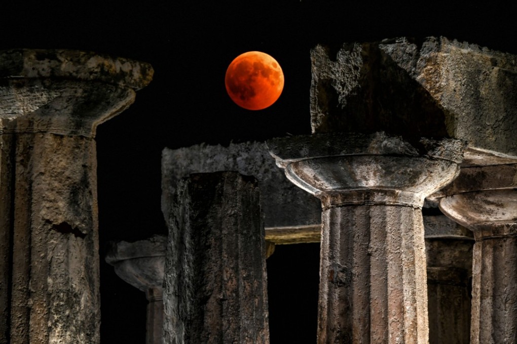 In this file photo taken on July 27, the “blood moon” eclipse is seen over the temple of Apollo in Corinth. Photo: Agence France-Presse
