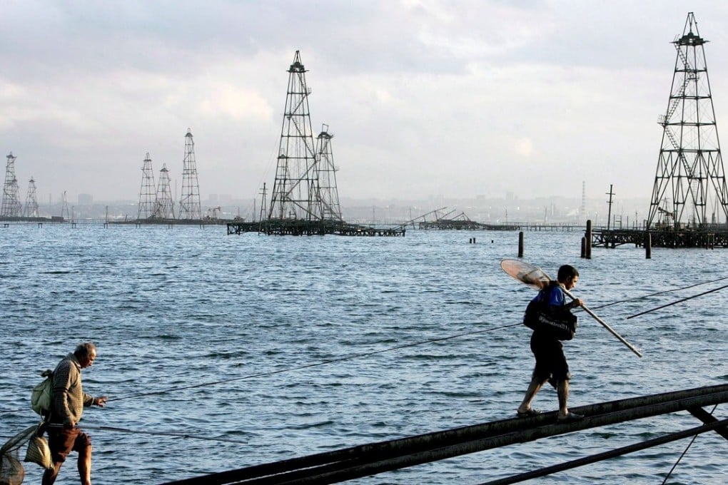 Two sailors walk in front of oil derricks on the Caspian Sea near Baku, Azerbaijan. Photo: EPA