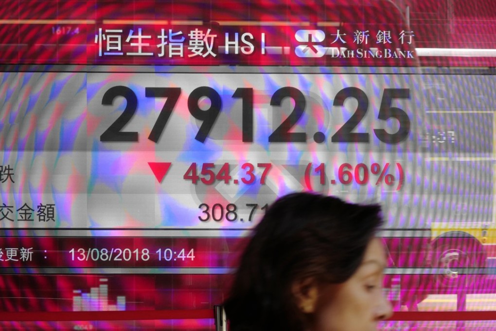 A woman walks past a bank electronic board showing the Hong Kong share index outside a Hong Kong local bank on Aug. 13, 2018. Photo: AP
