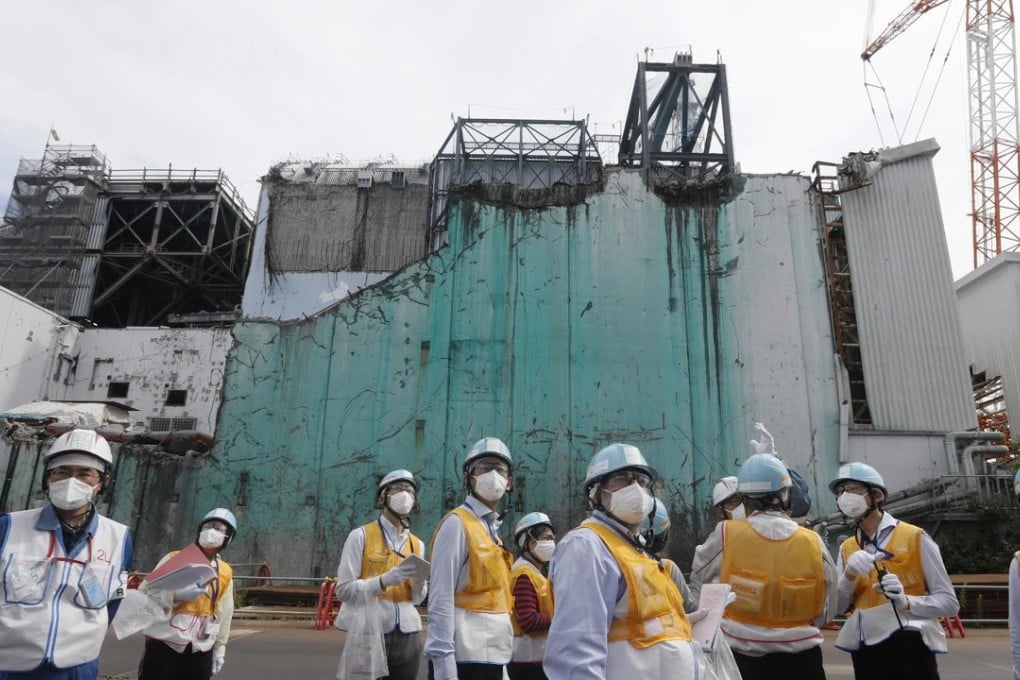Foreign journalists being briefed about decommissioning works between reactor unit 2 and unit 3 (in background) at the tsunami-crippled Tokyo Electric Power Company (TEPCO) Fukushima Dai-ichi nuclear power plant in Okuma, Fukushima prefecture. Photo: AFP