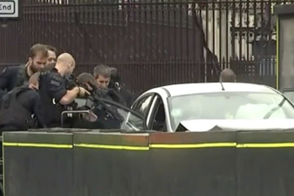 Armed police point guns at the car after it crashed into security barriers outside the Houses of Parliament in London. Photo: AP