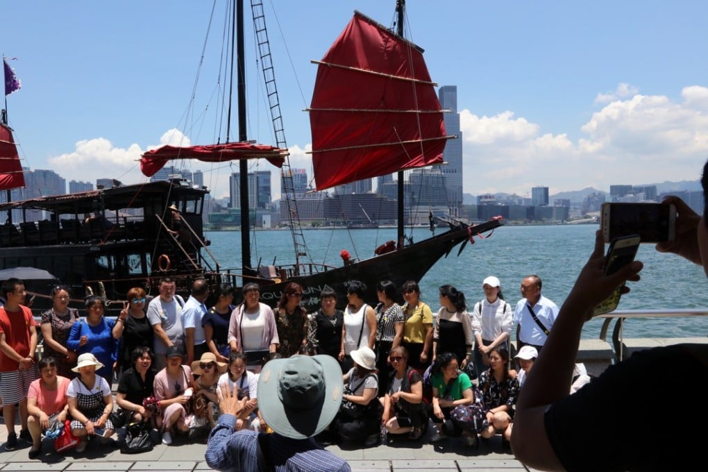 Tourists pose for a photo with a junk boat in the background at the Golden Bauhinia Square in Wan Chai. Photo: Felix Wong