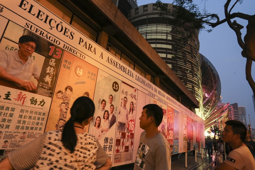 Passersby look at posters for the Legislative Assembly election in Macau, on September 17, 2017. The 33-seat assembly has 14 directly elected members, while 12 are indirectly elected and seven appointed by the Chief Executive of Macau. Photo: Dickson Lee