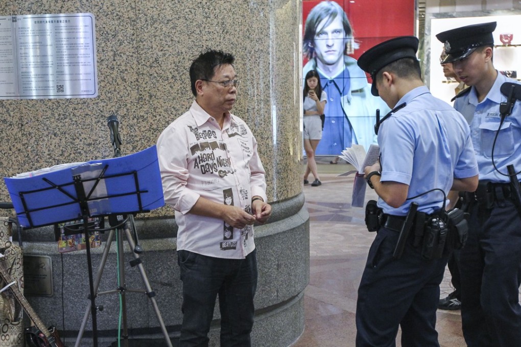 A street performer being questioned by Hong Kong Police at Times Square in Causeway Bay. Photo: Roy Issa