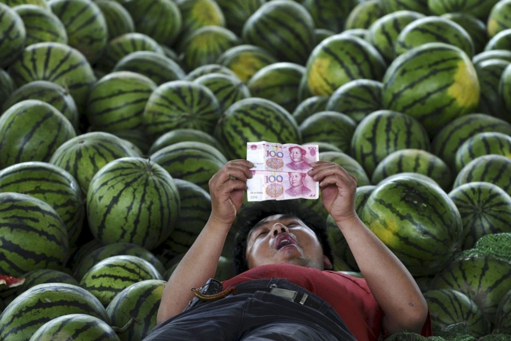 A watermelon vendor looks at yuan banknotes at a market in Changzhi, Shanxi province. The Chinese currency on Wednesday weakened to a 20-month low. Photo: Reuters