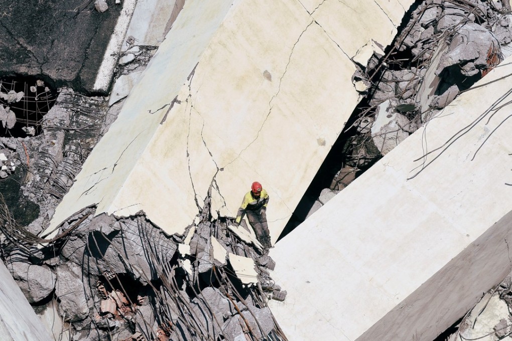 A rescue worker is dwarfed by rubble from the collapsed Morandi bridge in the port city of Genoa, Italy, on Tuesday. Photo: Reuters