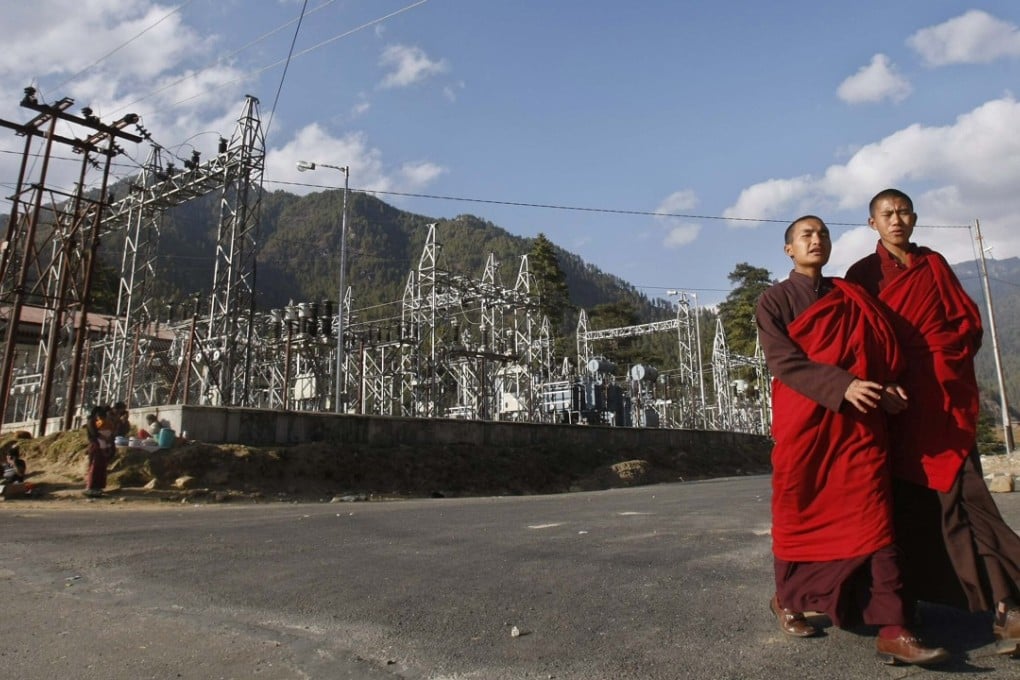 Buddhist monks pass a power station in Bhutan’s capital of Thimphu. Photo: Reuters