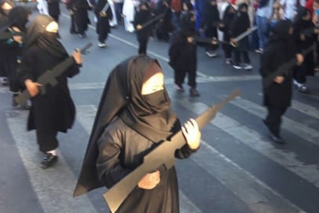 In the parade young girls wore niqab-style black veils and carried cardboard cut-outs of guns. Photo: Twitter