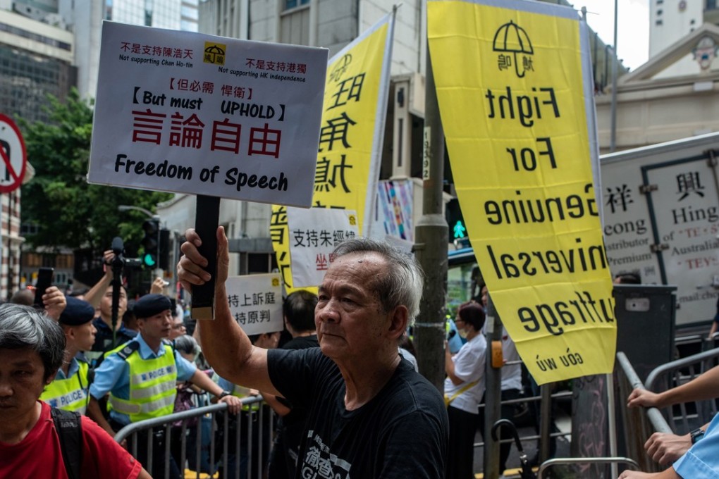 Demonstrators outside the FCC hold up placards in support of freedom of speech and universal suffrage, ahead of Andy Chan’s speech at the club on August 14. Photo: AFP