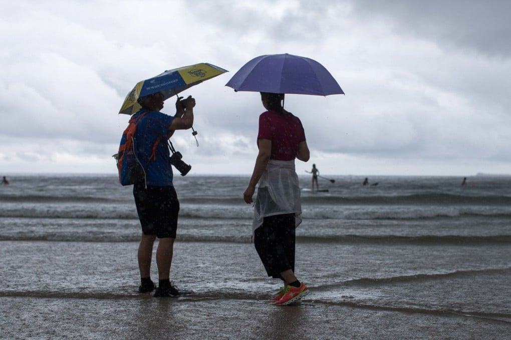 Hikers take pictures on Big Wave Bay beach during a downpour in Hong Kong on August 10. As a coastal city with a subtropical climate, Hong Kong is especially vulnerable to climate change. Photo: EPA-EFE