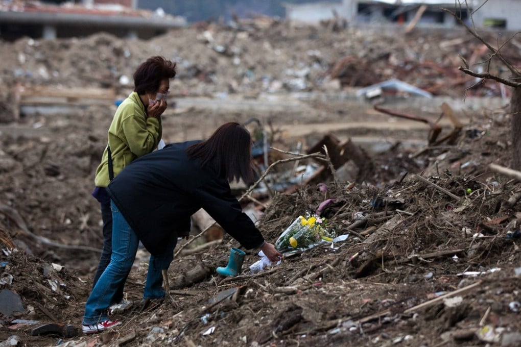 Family members who lost children at the Okawa Elementary School, in Ishinomaki, offer flowers at the place where many of the bodies were discovered. Picture: AFP