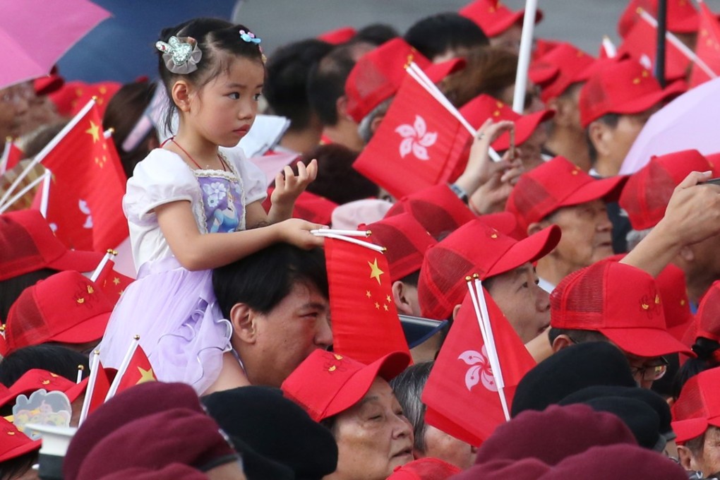 A child is carried during the flag-raising ceremony at the Golden Bauhinia Square in Wan Chai to mark the 21st anniversary of the establishment of the Hong Kong Special Administrative Region. Photo: David Wong