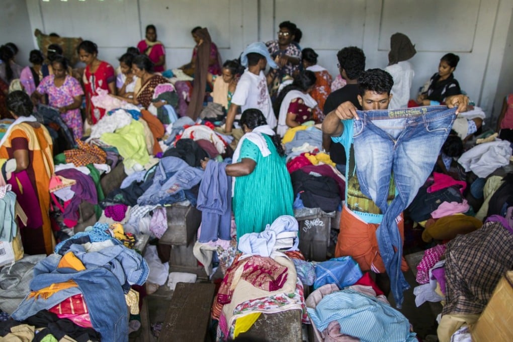 Flood victims search through donated clothing at a relief camp set up at Sree Narayana College Cherthala. Photo: Bloomberg.