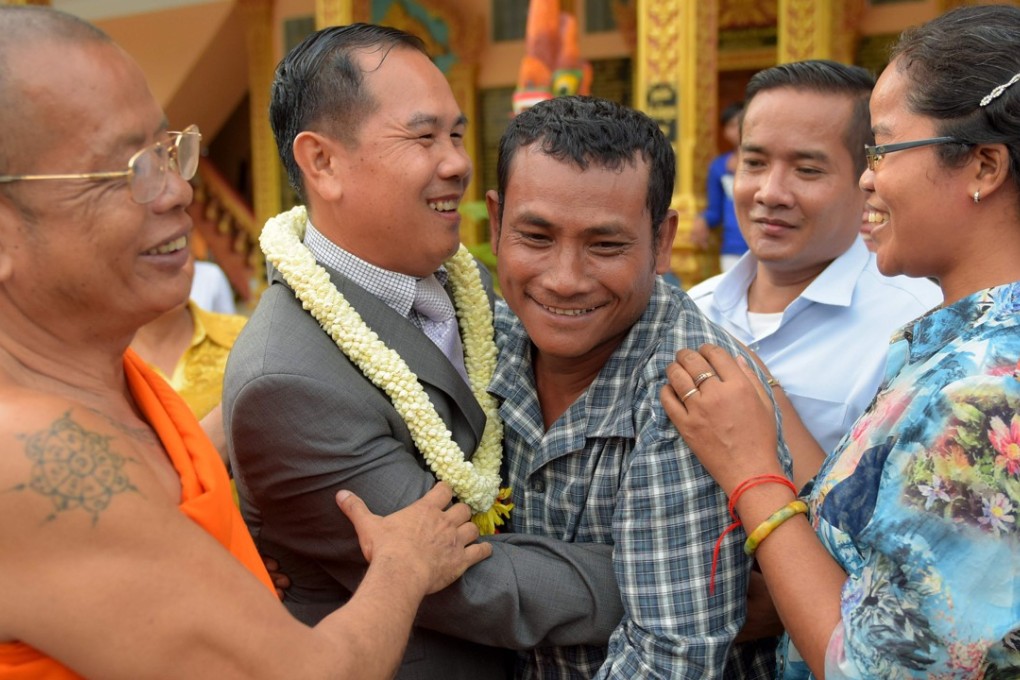 Former Cambodian opposition lawmaker Um Sam An (2nd L) hugs a land rights activist after he was released by royal pardon. Photo: AFP