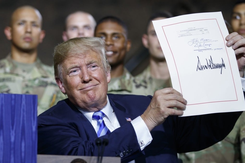 President Donald Trump signs a defence policy bill named for John McCain. Photo: AP