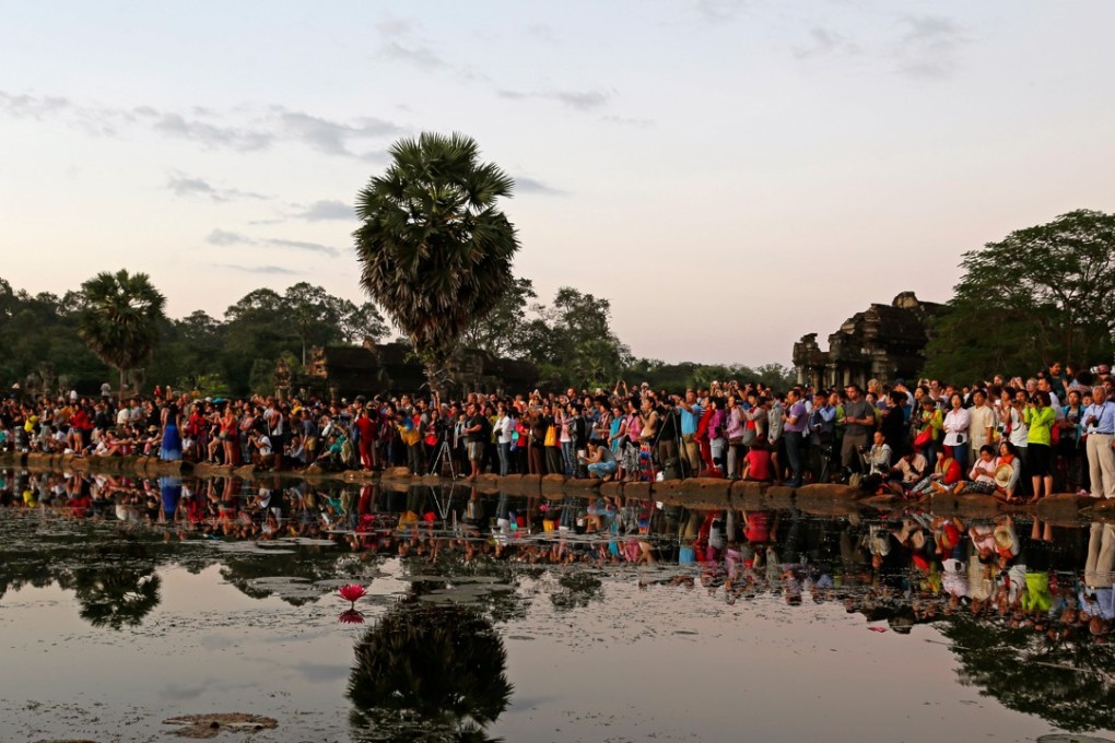 Tourists crowd round the lake at Angkor Wat temple to watch sunrise. Photo: Alamy