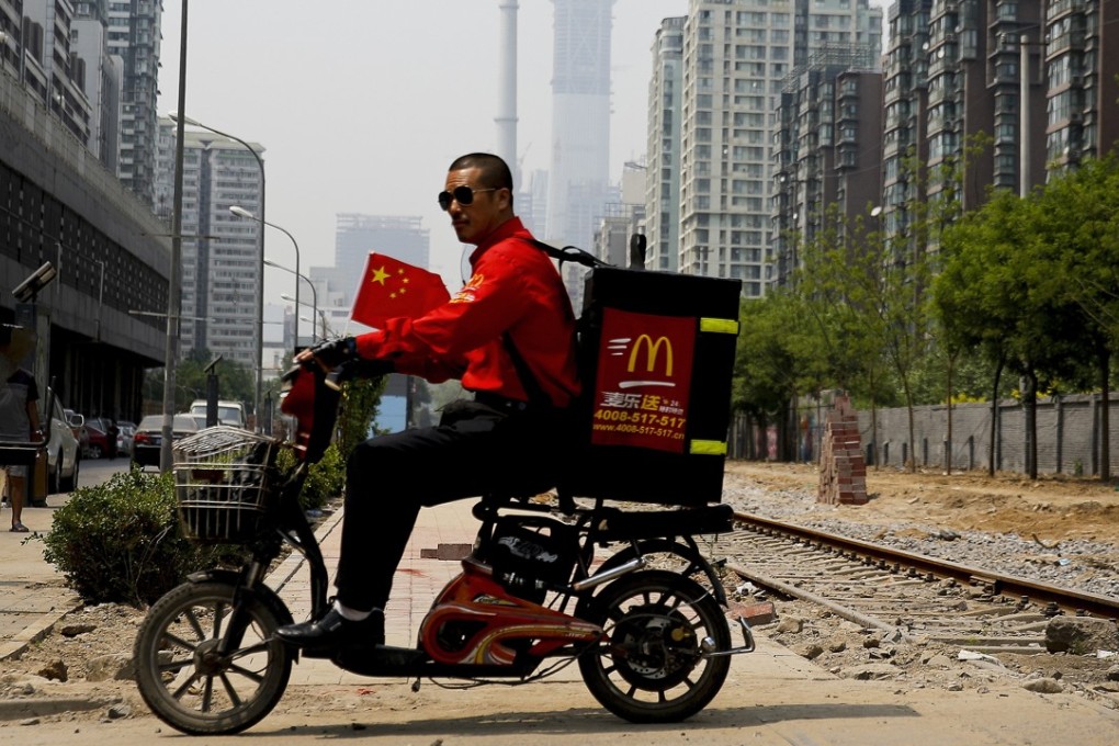 A McDonald’s delivery man rides past an abandoned railway track near residential buildings in Beijing in May 2017. Photo: AP