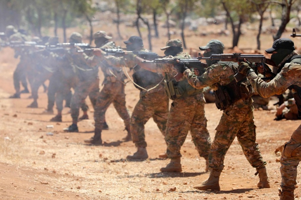 Syrian rebel fighters fire AK-47 rifles as they attend a mock battle in anticipation of an attack by the regime on Idlib province and the surrounding countryside, during a graduation of new Hayat Tahrir al-Sham (HTS) members at a camp in the countryside of the northern Idlib province on August 14, 2018. Photo: Agence France-Presse