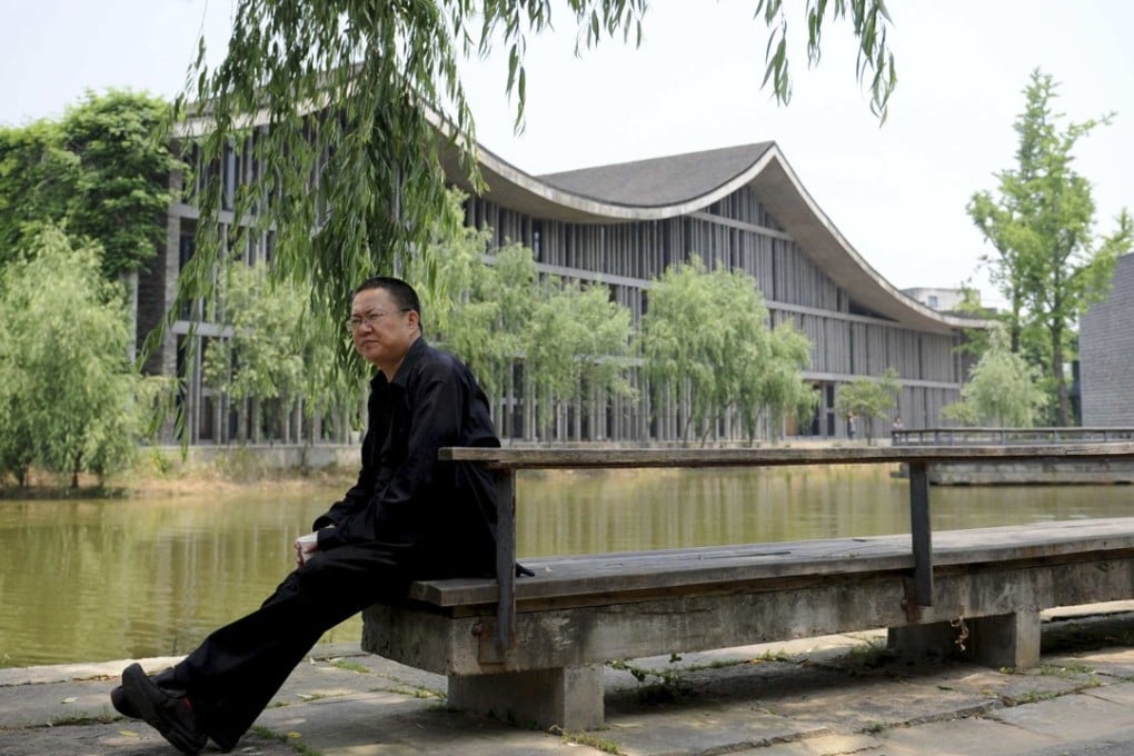 Pritzker Prize-winning architect Wang Shu sitting on a bench at the Xiangshan Campus, which he and his wife designed, at the China Academy of Art in Hangzhou. Photo: Reuters