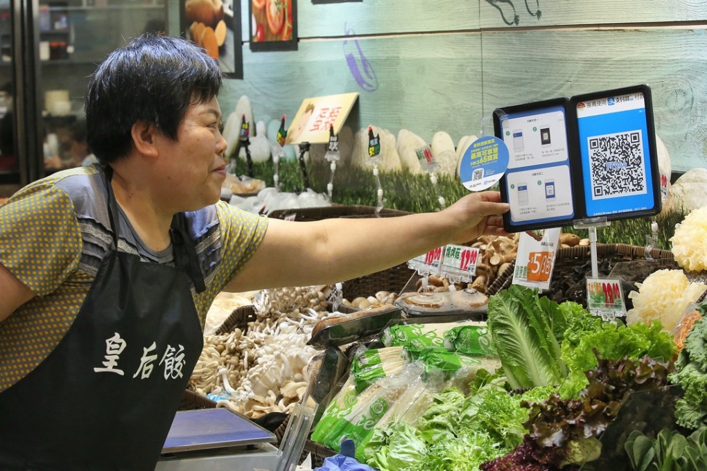 A vendor shows off the quick response (QR) code and payment instructions for Ant Financial Services Group's Alipay at her stall at Po Tat Market in Sau Mau Ping. Photo: SCMP