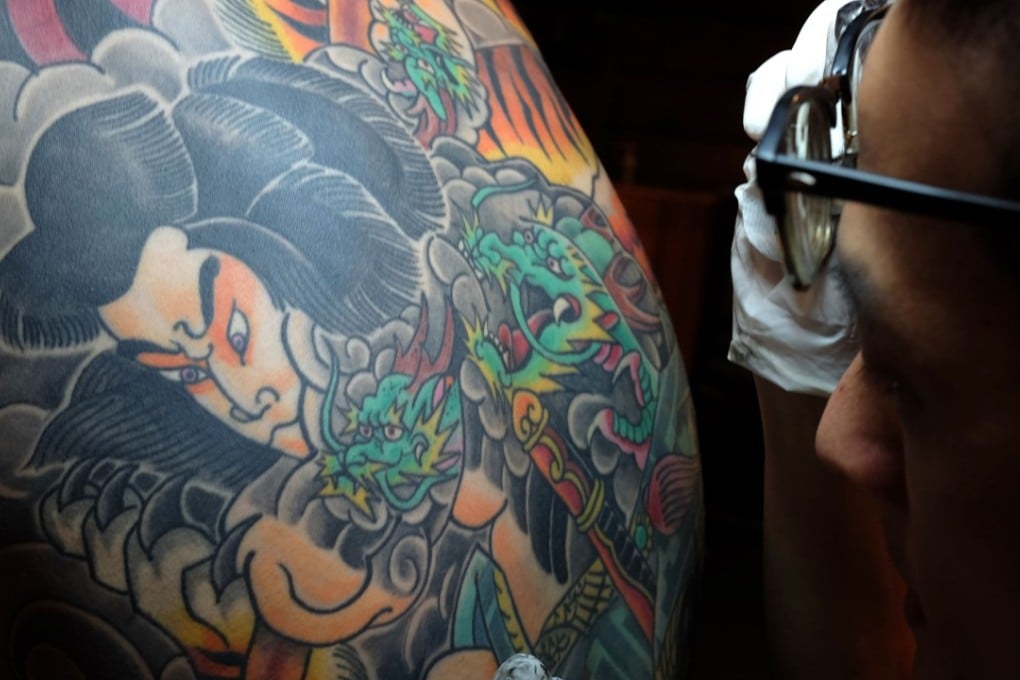 Tattoo artist Bobo Chen inspects the inked back of his client Micky Peng. Photo: AFP