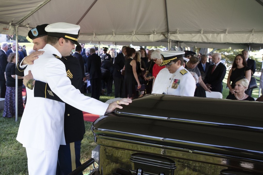 In this image provided by the family of John McCain, Jimmy McCain hugs his brother Jack McCain, touching the casket, as Cindy McCain, watches during a burial service for John McCain at the cemetery at the United States Naval Academy in Annapolis, Maryland, on Sunday. Photo: AP