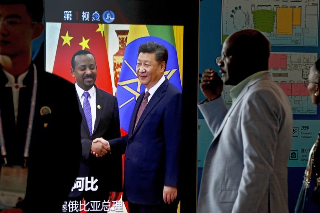 African delegates walk by a screen panel showing a footage of Chinese President Xi Jinping with Ethiopia's Prime Minister Abiy Ahmed. Photo: AP