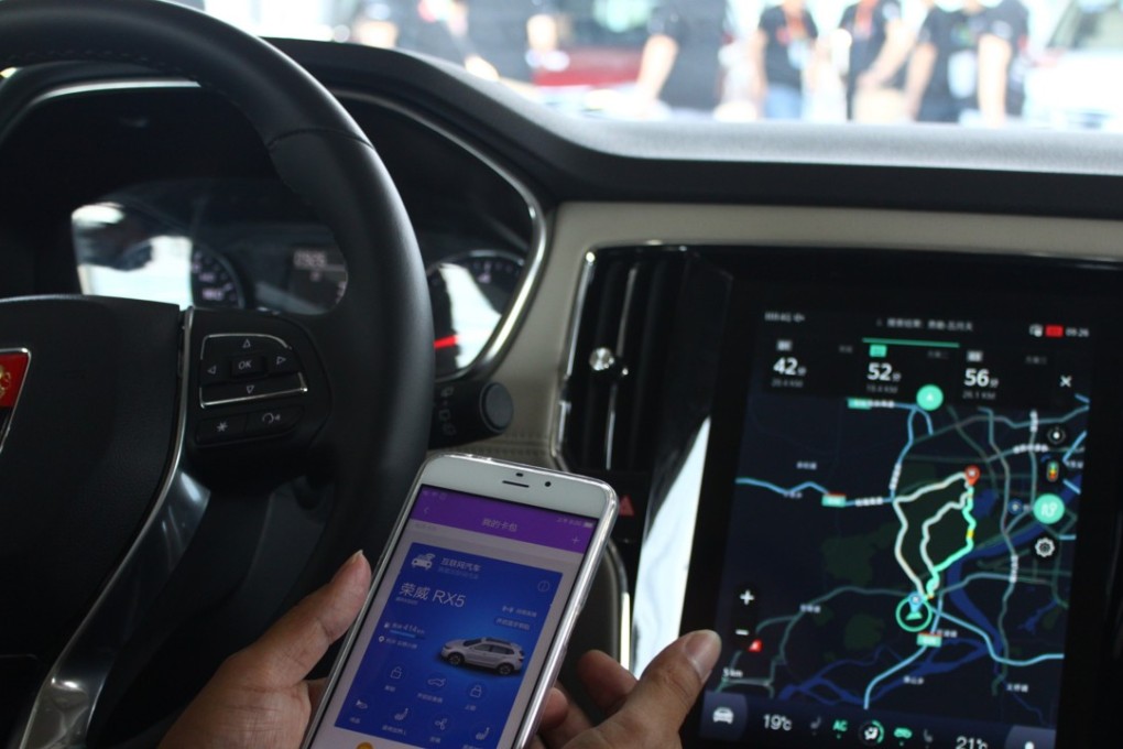 A driver demonstrates how to connect SAIC's Roewe RX5 sport utility vehicle with his mobile phone using Alibaba's YunOS operating system. Photo: SCMP