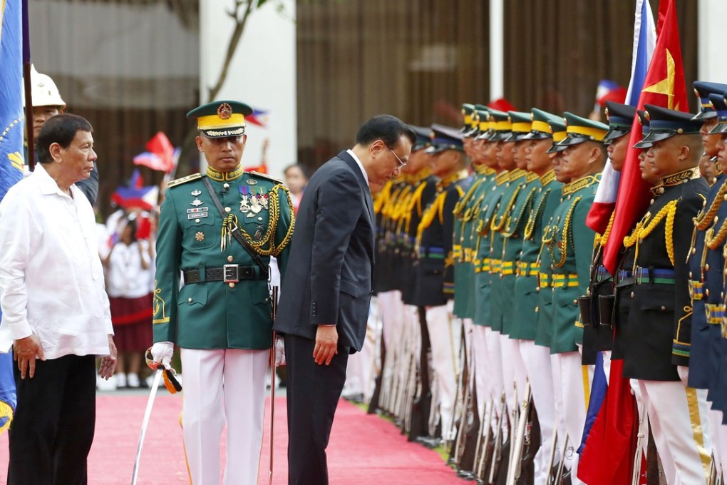 Chinese Premier Li Keqiang pauses to his pay respects to the Chinese and Philippine flags as he reviews troops with Philippine President Rodrigo Duterte (left) during a welcome ceremony at Malacanang Palace grounds in Manila on November 15, 2017. Duterte has fostered closer relations with China than his predecessor. Photo: AP