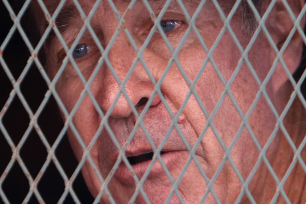 Australian filmmaker James Ricketson talks from inside a prisoner truck upon his arrival at Phnom Penh Municipal Court in Cambodia. Photo: AP