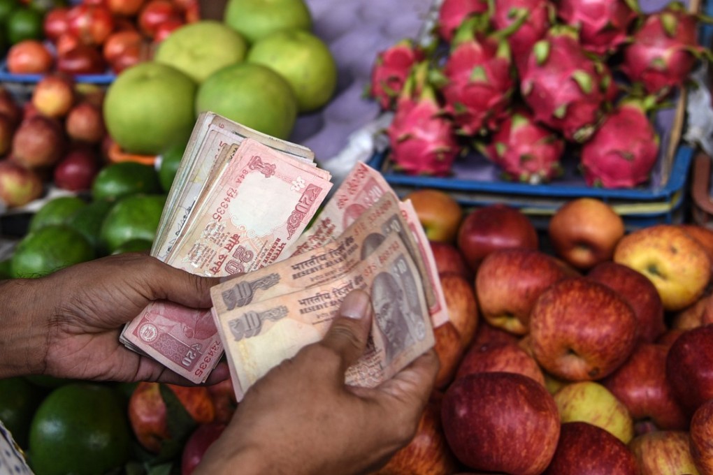 A vendor counts rupees at a vegetable market in Mumbai. Photo: Xinhua
