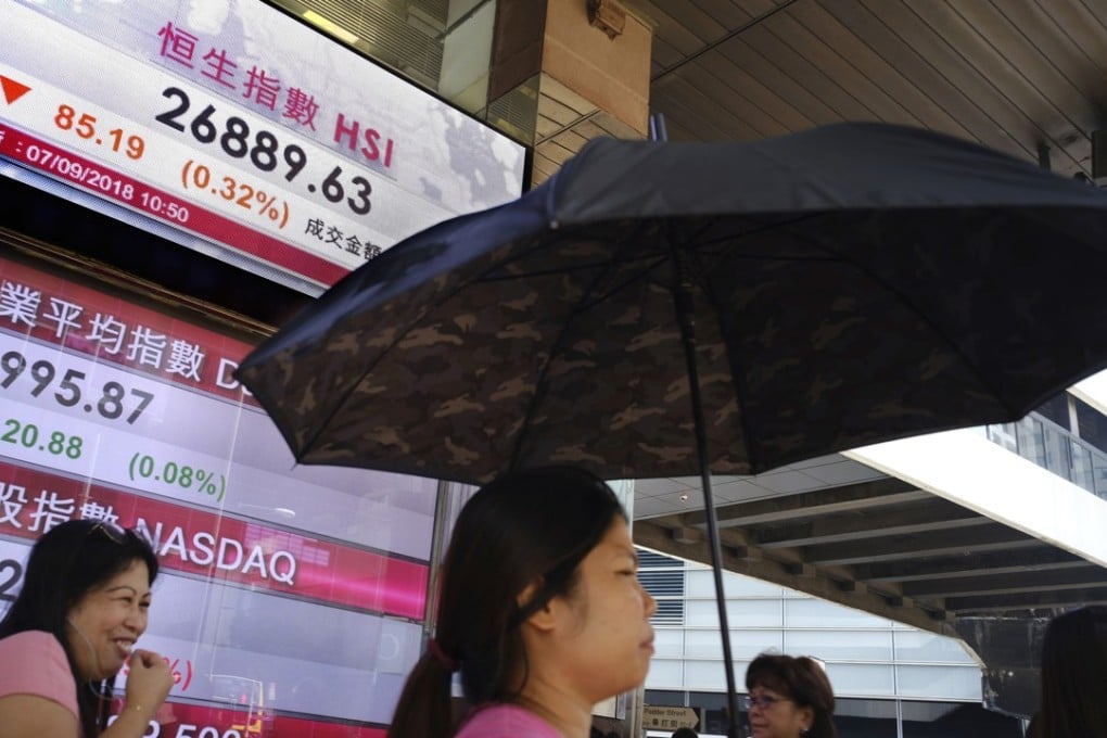 People walk past an electronic board showing the performances of Hong Kong share indexes outside a local bank in the city centre. Photo: AP