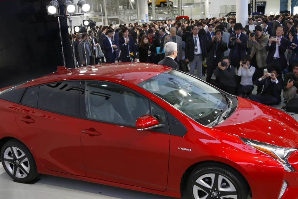 Toyota Motor Corp. Executive Vice President Mitsuhisa Kato posing with a new Toyota Prius at the automaker's showroom in Tokyo on Wednesday, December 9, 2015. Photo: AP