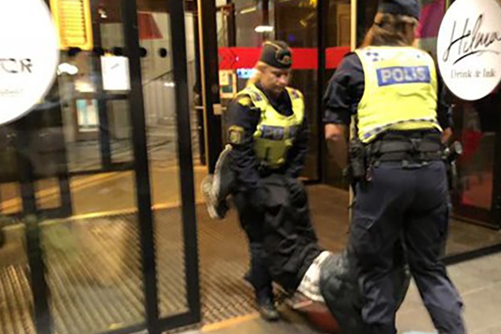 Swedish police officers carry one of the Chinese tourists out of the Stockholm hostel. Photo: Handout